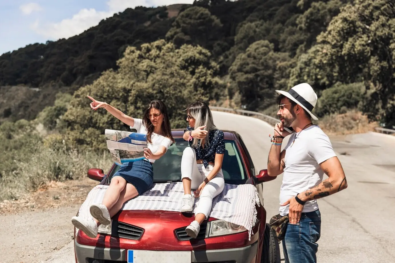 Подруги обсуждают направление по карте перед мужчиной, разговаривающим по мобильному телефону.